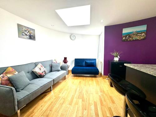 un soggiorno con divano grigio e pareti viola di The Crib - 1 Bedroom Apartment Central London by Wild Boutique a Londra