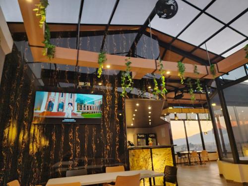 Hotel Luna de Plata Aeropuerto في كويتزالتنانغو: غرفة طعام مع تلفزيون على جدار مع نباتات
