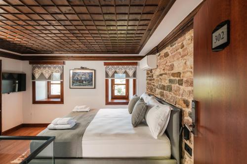 Bett in einem Zimmer mit Ziegelwand in der Unterkunft DAM Stone Boutique Hotel in Gjirokastër