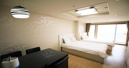 a bedroom with two beds and a desk and a window at High Castle Resort in Jeongseon