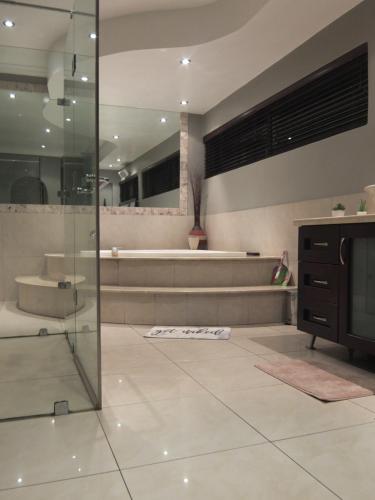 a bathroom with a glass shower and a tub at Korsmans Delights - Large House in Benoni