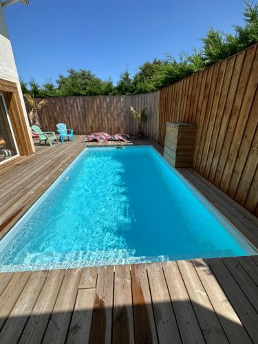 - une piscine dans un jardin avec une clôture en bois dans l'établissement Maison de vacances au centre Biscarrosse, à Biscarrosse
