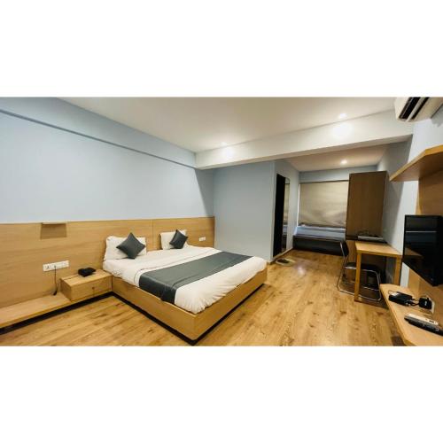 a bedroom with a bed and a desk and a television at The Berlin in Gandhinagar