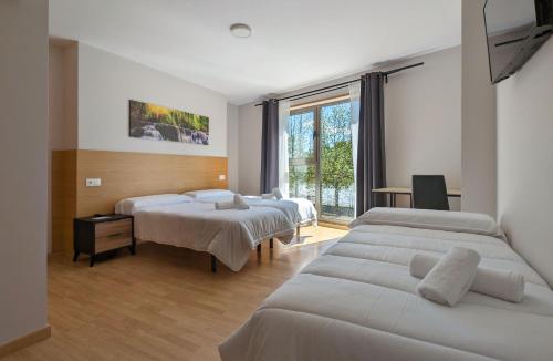 アルスーアにあるDuerming Villa de Arzúaのベッド3台と窓が備わるホテルルームです。