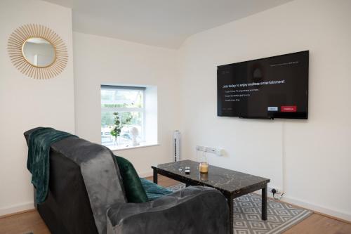 a living room with a couch and a table and a tv at Corporate-Friendly 2BR Apartment in Leeds, Near Kirkstall Shopping Centre in Leeds