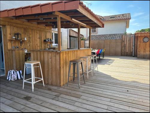 une terrasse en bois avec des tabourets et un bar dessus dans l'établissement Maison de vacances au centre Biscarrosse, à Biscarrosse