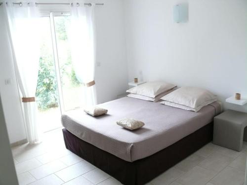 une chambre avec un grand lit avec deux oreillers dessus dans l'établissement TARRA DI ALZU - T2 en RDJ villa, à Porto-Vecchio