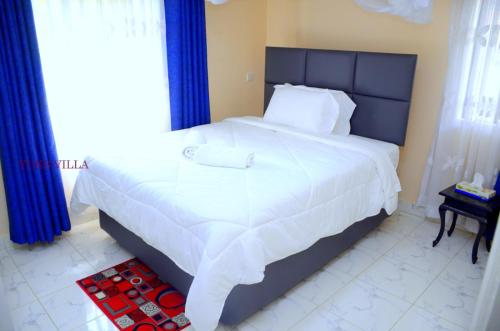 a bedroom with a large white bed with blue curtains at Yuks Villa in Kisumu