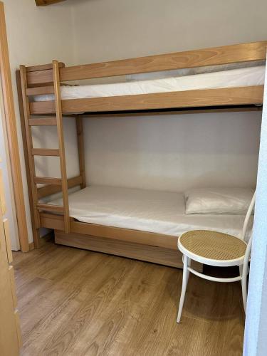 Cette chambre comprend deux lits superposés, une chaise et une table. dans l'établissement HOLIDAYLAND 436 VILLA T2 MEZZANINE 6 couchages climatisé NARBONNE PLAGE, à Narbonne-Plage