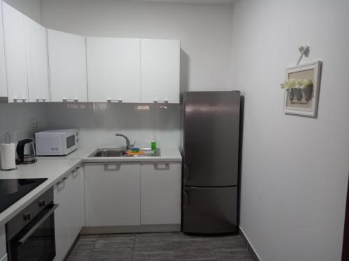 Una cocina con gabinetes blancos y un refrigerador negro. en Apartman Iva, en Gradac
