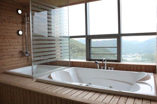 a large bath tub in a room with windows at High Castle Resort in Jeongseon