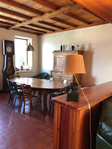 une salle à manger avec une table, des chaises et une horloge dans l'établissement Le Presbytère - Des vacances à la montagne, à Saint-Laurent-du-Cros