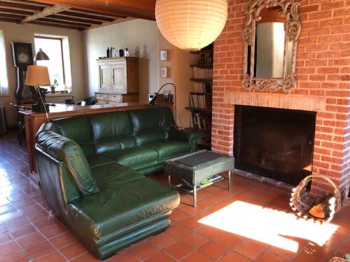 - un salon avec un canapé vert et une cheminée dans l'établissement Le Presbytère - Des vacances à la montagne, à Saint-Laurent-du-Cros