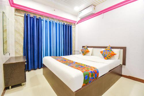 1 dormitorio con 1 cama con cortinas azules en FabHotel The Horizon I, en Lonavala