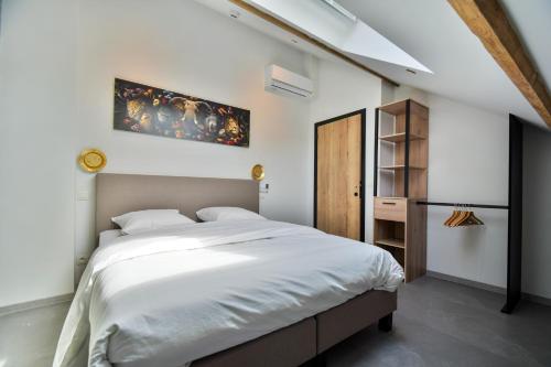 a bedroom with a large white bed and a wooden cabinet at Les Gîtes de Huy - 3 gîtes dans le centre de Huy in Huy