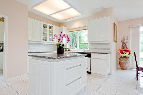 una cucina bianca con armadi bianchi e fiori sul bancone di Harmony House a Richmond