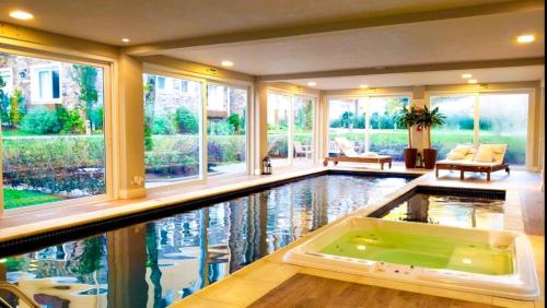 an indoor pool with a tub in a house at Apto LINDO com lareira, piscina aquecida e jacuzzi in Gramado