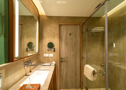 ein Bad mit einem Waschbecken und einer Dusche in der Unterkunft Nidhivan Sarovar Portico Vrindavan in Vrindāvan