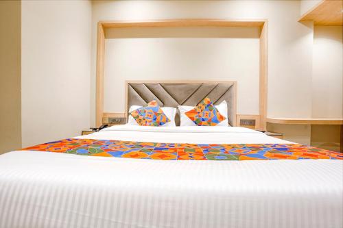 a large white bed with colorful pillows on it at FabHotel Aqua Rooms in Mumbai