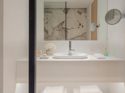 La salle de bains blanche est pourvue d'un lavabo et d'un miroir. dans l'établissement The Roc Club, à Athènes