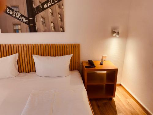 a hotel room with a bed and a phone on a night stand at Stay Inn Central Station in Frankfurt/Main
