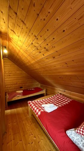 a room with a red bed in a wooden cabin at Domki Na Złotym Groniu in Istebna