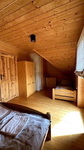 an attic room with a bed and wooden walls at Domki Na Złotym Groniu in Istebna