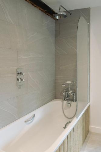 a bathroom with a bath tub with a shower at 2 Henham Barns in Beccles