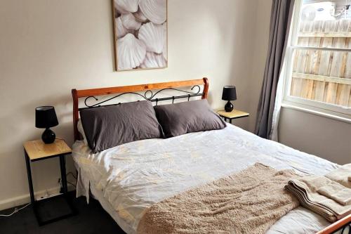 a bedroom with a bed with two lamps on tables at Charming Home Near Melbourne Airport & CBD in Melbourne