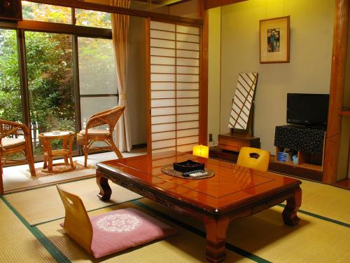 sala de estar con mesa de madera y sillas en Takarabune Onsen Yumoto Kotobuki, en Takashima