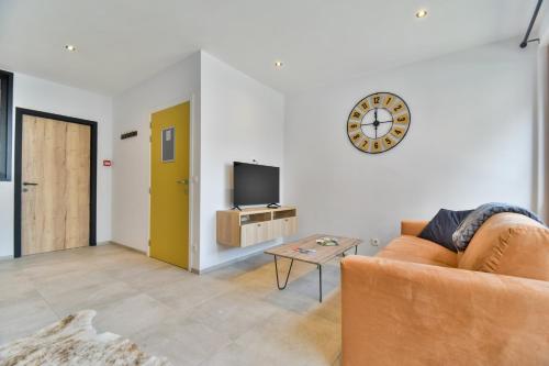 a living room with a couch and a clock on the wall at Les Gîtes de Huy - 3 gîtes dans le centre de Huy in Huy
