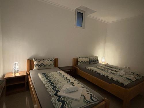 a bedroom with two beds and a night stand with two lamps at Apartmani "MARIJA" Golubac in Golubac