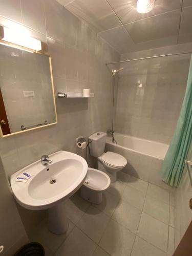 a bathroom with a sink and a toilet and a tub at Hotel El Pescador in Sant Pere Pescador