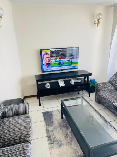 uma sala de estar com 2 sofás e uma televisão de ecrã plano em Sea View Heights em Amanzimtoti