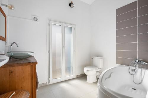 une salle de bain avec une baignoire, des toilettes et un lavabo dans l'établissement L'Ostal de Pomérols - Grande maison pour 10, à Pomérols