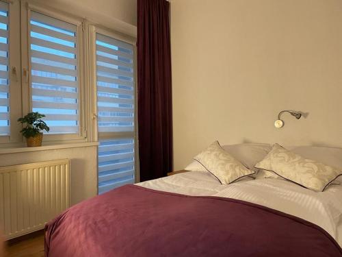 a bedroom with a bed and a window with shutters at Koral Świnoujście in Świnoujście