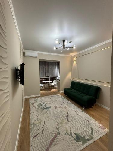 sala de estar con sofá verde y piano en Comfort City Apart #1, en (( Gornyy Gigant ))