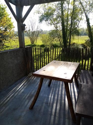 una mesa de picnic de madera en una terraza con una valla en A la campagne, à 12mn de l'océan, en Locoal-Mendon