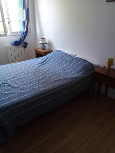 1 dormitorio con 1 cama con edredón azul y ventana en A la campagne, à 12mn de l'océan, en Locoal-Mendon
