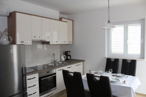 a kitchen with white cabinets and a table with chairs at Slano Bay Apartments in Slano