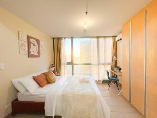 um quarto com uma cama e uma grande janela em Deluxe 1br - Bgc Uptown, Netflix, Pool #oursw30b2 em Manilla