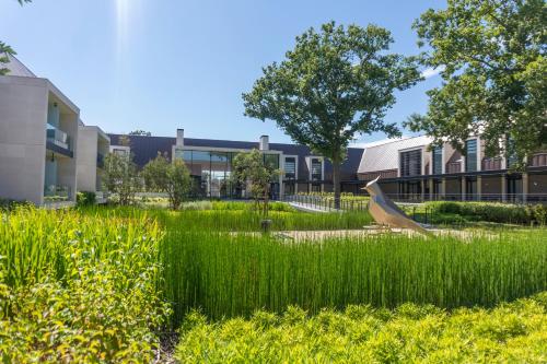 a field of tall grass in front of a building at Le Domaine des Vanneaux Golf et Spa Mgallery in LʼIsle-Adam