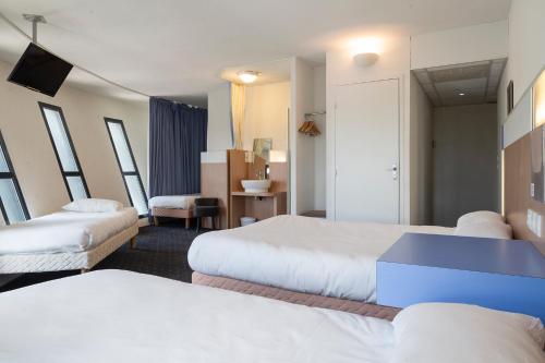 a hotel room with two beds and a television at The Originals Access, Hôtel Millau Sud in LʼHospitalet-du-Larzac