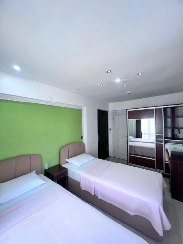 a bedroom with two beds and a green wall at Dardanos Pension in Hamidiye