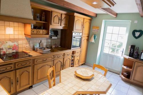 une cuisine avec des armoires en bois et une table et des chaises dans l'établissement La Charmille - Grande maison bourgeoise, 35 Kms du Futuroscope, à La Puye