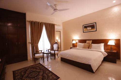 a bedroom with a large bed and a window at Ambassador Hotel Clifton in Karachi
