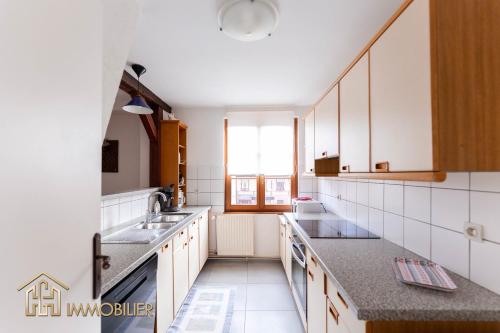 a kitchen with white cabinets and a large window at Au Bonheur des Anges Appartement 2 chambres avec terrasse in Colmar