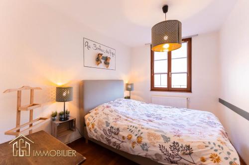 a bedroom with a bed and a table and a window at Au Bonheur des Anges Appartement 2 chambres avec terrasse in Colmar