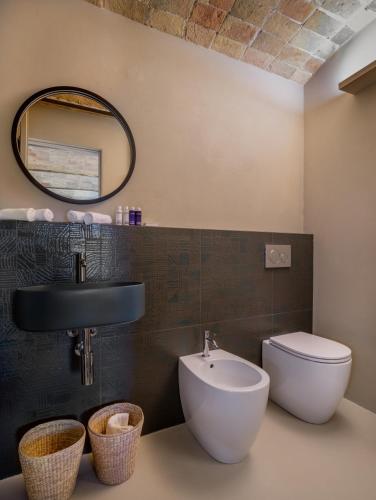 a bathroom with a toilet and a sink and a mirror at Relais Dal Cavaliere in Castellino