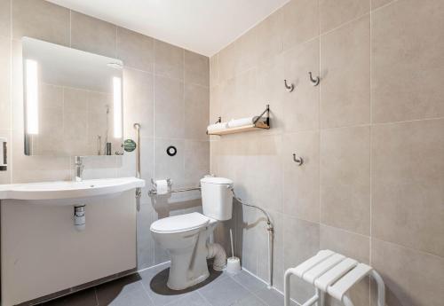 La salle de bains est pourvue de toilettes blanches et d'un lavabo. dans l'établissement B&B HOTEL Valenciennes Sud, à Valenciennes